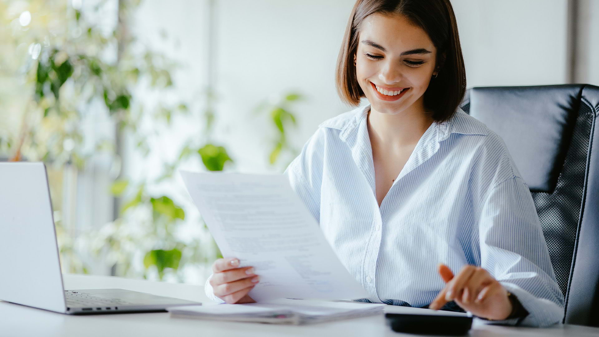 A woman sitting at her desk calculating her finances.